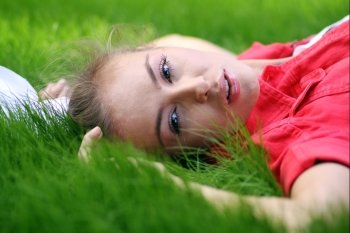 Cute young female lying on grass field at the park 