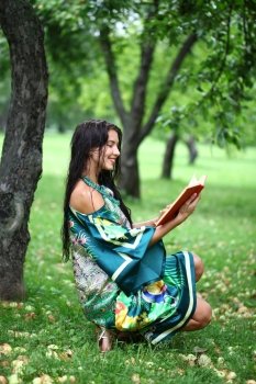 Portrait of beautiful young blonde girl reading a book in the park 