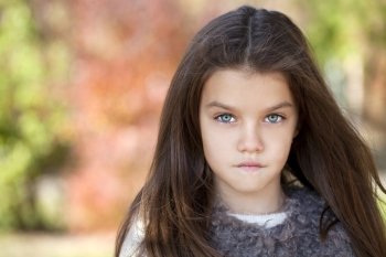 Close up portrait of a beautiful nine year old little girl in autumn park