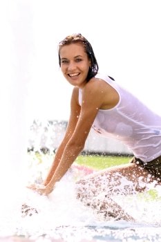 Young sexy woman bathes in a city fountain 