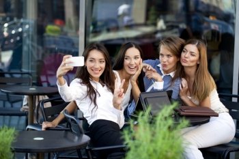 Selfie Four women sitting in a cafe on the street