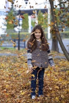 Young beautiful little girl with yellow leaves in autumn park
