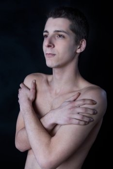 portrait of young man with arms cross against black background