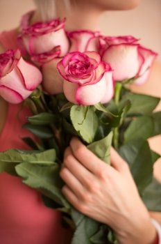 Unrecognizable woman holding bouquet of pink roses. She is very satisfacted. Valentine's day or international women's day celebration.