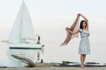Free woman enjoying freedom feeling happy at beach at morning. Beautiful serene woman and welcoming yacht and sailor with arms opened outstretched up. Hispanic Caucasian female model