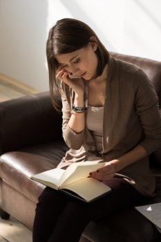Portrait of pensive thinking business woman talking mobile phone and holding notepad or organizer and planning at her office