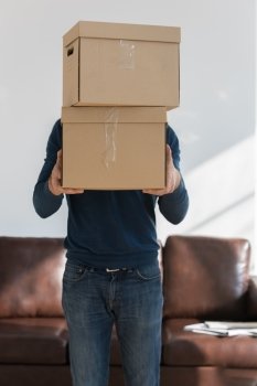 Man holding cardboard boxes at home - moving in new home and mortgage concept