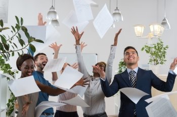 Group of excited multi racial businesspeople throwing papers in office