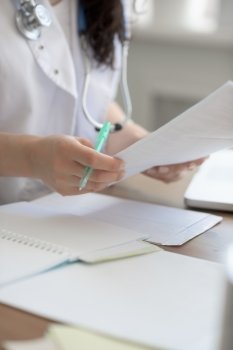 Female doctor taking notes during looking at patient medical tests at her office