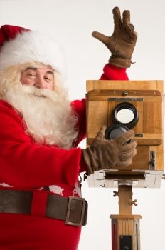 Santa Claus taking picture with old wooden camera. Closeup portrait isolated on white background