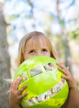Little girl playing with green ball in the park. Pictures of sports exercises on the ball. Virtual trainer concept
