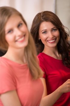 Two pretty Women shopping clothes. Shopper looking at camera indoors in store. Beautiful happy smiling caucasian females models.