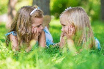 Two little cute girls on lawn in the park