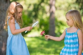 Children with a magnifying glass. Two little sisters of friends looking through magnifier at flower