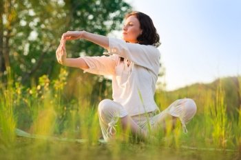 Stretching woman in outdoor exercise smiling happy doing yoga stretches. Beautiful happy smiling sport fitness model outside on summer / spring day