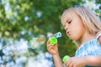 little girl with soap bubbles having fun outdoors
