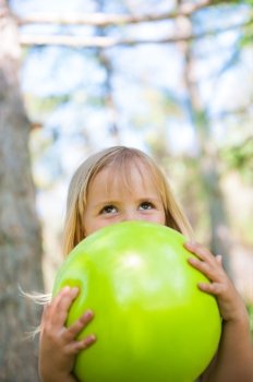 Little girl playing with green ball in the park