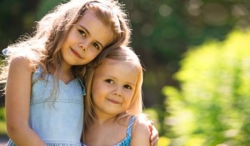 Outdoor portrait of two embracing cute little girls