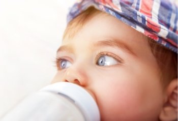 Closeup portrait of cute little baby boy drinking milk isolated on white background, healthy nutrition for children
