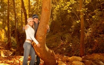 Photo of young lovely family hugging in the forest, happy couple enjoying autumn nature, autumnal holidays, loving relationship, pretty girl with nice guy walking in autumn park, love concept
