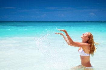 Cheerful female on the beach, splashing refreshing water, enjoying summer holidays on the beach resort, happy active lifestyle