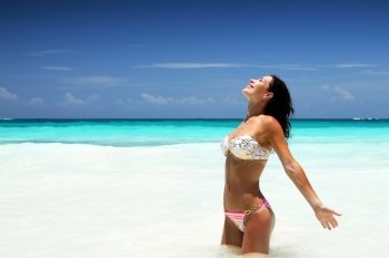 Beautiful woman on the beach, standing in sea, enjoying bright sun light, happy summer holidays, travels to Caribbean Sea, Cancun, Mexico, North America, enjoying life
