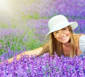 Pretty woman lying down on lavender field at sunny day, beautiful female sitting on purple flowers meadow, cheerful smiling girl enjoying violet floral glade and sun light, portrait of young lady