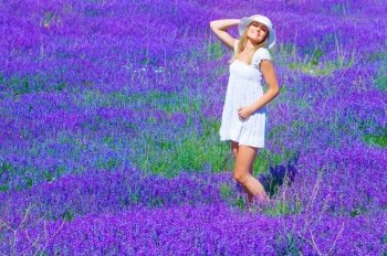Pretty girl tanning in lavender glade, enjoying bright sun light and purple flowers landscape, having fun outdoors in summer time