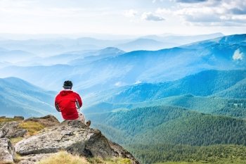 Young man sits and meditates on the top of mountain