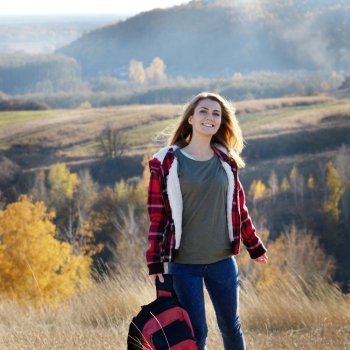 Beautiful happy smiling young woman with backpack outdoors