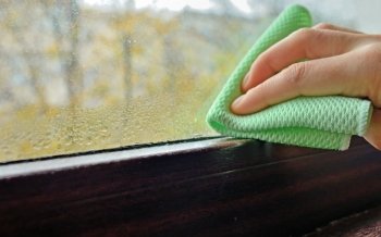 Woman cleaning water  condensation on window