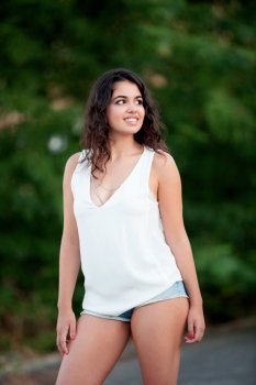 Beautiful brunette girl with shorts relaxing in the park wiht many plants of background