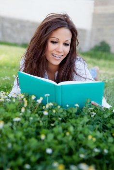 Young woman reading a book lying on the grass