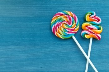 Two lollipops with many colors in a spiral on a wooden background