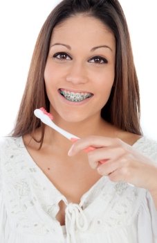 Attractive young woman with brackets cleaning her teeth isolated on a white backgroung