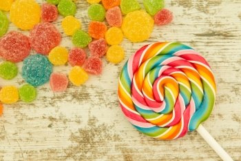 Colorful jelly beans and lollypop close to wallpaper
