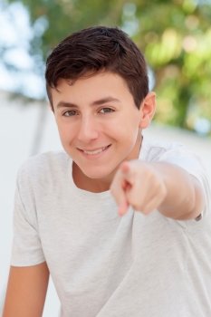 Casual teenager boy indicating at camera outdoor