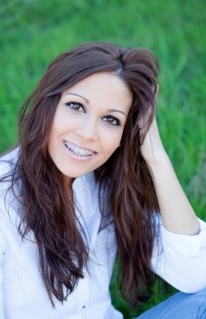 Brunette cool girl with brackets sitting on the grass