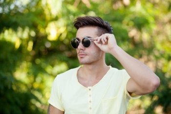 Attractive guy in the park with sunglasses and yellow t-shirt