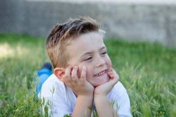 Pensive funny kid lying on the grass