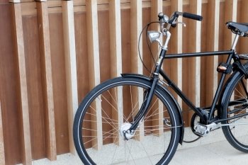 Black bicycle supported on a modern wall with wooden bars