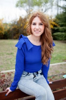 Attractive cool woman dressed in blue sitting on a bank at outside