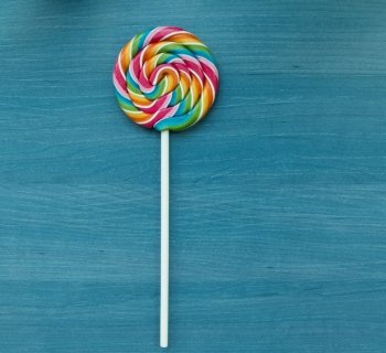 Nice lollipop with many colors in a spiral on a wooden background
