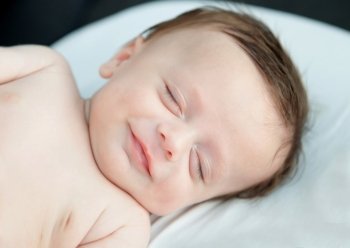 Tender baby smiling while nap in the crib