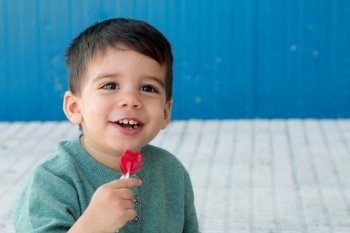 Happy toddler on the street eating a lollipop