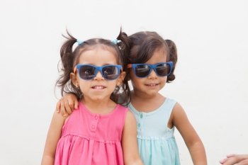Loving twin sisters two years with sunglasses outdoors playing