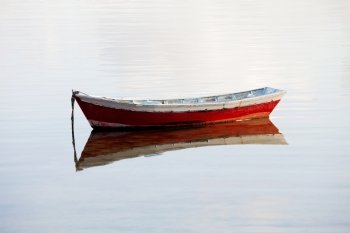 Lone red boat floating on a calm sea