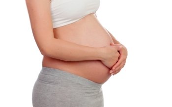 Pregnant woman stroking her belly isolated on a white background