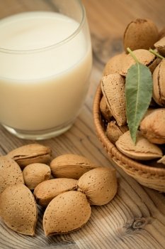 Almond milk with almonds on a wooden table and focus with shallow depth of field 