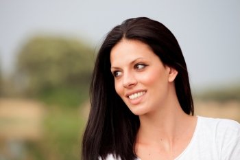 Young beautiful woman with brunette hair and perfect smile  posing in park 